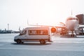 White VIP service van running on airport taxiway with big passenger airplane on background. Business class service at