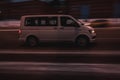 White volkswagen van vehicle on city road. Fast moving car on street at night. Delivery van fast delivers in a city. Compliance