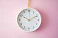 white wall clock hanging against a pale pink wall Royalty Free Stock Photo