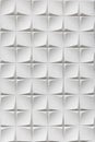 A white wall covered with three-dimensional tiles forming a geometric pattern. Textured plaster Royalty Free Stock Photo