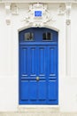 White wall of the house with a closed blue wooden door in Paris, France