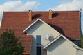 White wall of a private house with windows under a red tiled roof with chimneys