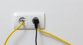 White wall socket with yellow and black electrical cords plugged in electrical outlet power outlet Royalty Free Stock Photo