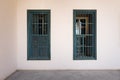 White wall with grunge windows with wooden green shutters and wrought iron bars and marble floor Royalty Free Stock Photo