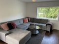 Livingroom with big grey sofa and flatscreen TV white walls