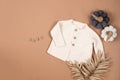 White warm knitted sweater with white, brown bodysuits on beige background. Collection of cute baby clothes for cold weather Royalty Free Stock Photo