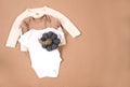 White warm knitted sweater with white, brown bodysuits on beige background. Collection of cute baby clothes for cold weather Royalty Free Stock Photo