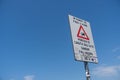 White warning sign alerting for the danger of falling in the sea on a blue sky background