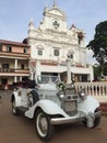 A white washed old church in Goa with an antique car