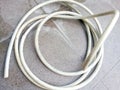 a white water hose coiled on the floor of a yard in the afternoon Royalty Free Stock Photo