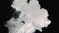 White watercolor ink in water on a black background. Waves of milky ink and splashes of white paints in the water. White cloud of Royalty Free Stock Photo