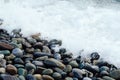 White wave washing the stones of the shore. Background with beach of stone.