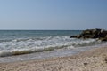 White waves breaking on sandy beach through gap in rocks on sea. Rock fragments on a wild beach Royalty Free Stock Photo