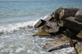 White waves breaking on sandy beach through gap in rocks on sea. Rock fragments on a wild beach Royalty Free Stock Photo