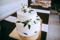 White wedding cake with buttercream icing  decorated with white roses and green branches with leaves Royalty Free Stock Photo