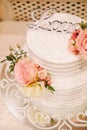 White wedding cake decorated with flowers: pink and ivory roses. Wooden sign: Love. Flat lay, top view, macro