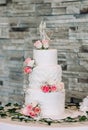 White wedding cake decorated with red roses and figurine in the shape of a bride and groom Royalty Free Stock Photo