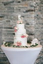 White wedding cake decorated with red roses and figurine in the shape of a bride and groom Royalty Free Stock Photo