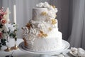 a white wedding cake with gold and white flowers on a table with candles and flowers on the tablecloth and a vase of flowers in