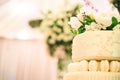 WHITE  WEDDING CAKE AT IMPRESSIVE COLOURFUL VENUE WITH BEAUTIFUL CANDY TABLES, FLORAL GREEN DECORATION, BLURRED BACKGROUND, YELLOW Royalty Free Stock Photo