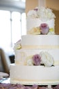 White wedding cake with yellow, white, and purple flowers. 4 tiers - wedding cake series