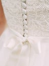 White wedding dress close up. Elegant lace, bow and small fabric-covered buttons, bridal details Royalty Free Stock Photo