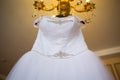 White wedding dress hanging on the chandelier. bride accessories. charges of the bride. bride`s morning