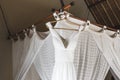 White wedding dress hanging inside room on baldachin with curtains
