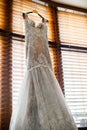 White wedding gown is hanging at the wooden jalousie Royalty Free Stock Photo