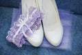 White wedding shoes for the bride and a purple garter on a blue background Royalty Free Stock Photo