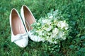 White wedding shoes on green grass. Beautiful bridal bouquet and snow-white freesias Royalty Free Stock Photo