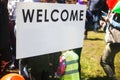 White Welcome sign in the street. Blurred people visiting an event in the city
