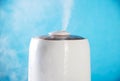 White wet steam from a humidifier on a blue background. Device for healthy air in the room, close-up Royalty Free Stock Photo