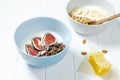 white wheat and chocolate granola with low-fat yogurt in a white bowl in a composition with a spoon, honeycombs, banana fig on