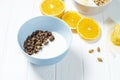 white wheat and chocolate granola with low-fat yogurt in a white bowl in a composition with a spoon, honeycombs, banana, orange on