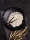 White wheat flour in a wooden spoon on a dark structural background on a plate made of black stone Royalty Free Stock Photo