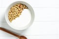 white wheat granola with low-fat yogurt in a white bowl in a composition with a spoon on white wooden background. Healthy