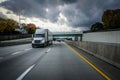 White 18 wheeler semi-truck on highway with storm clouds in the sky