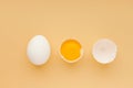 White whole chicken egg , yolk and empty cracked eggshell on yellow background, top view. Royalty Free Stock Photo