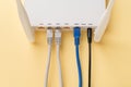 White Wi-Fi wireless router with connected network and power cables on a yellow background. Home and office wlan router with Royalty Free Stock Photo