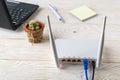White Wi-Fi wireless router near laptop on a white wooden table. Wlan router with internet cables plugged in on a table in a home Royalty Free Stock Photo