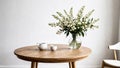 White wildflowers in paunchy vase on round wooden brown table against empty gray wall. Minimalistic interior. Scandinavian style