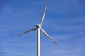 A white wind turbine with three propellers against the blue sky