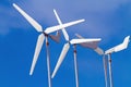 White wind turbines producing alternative energy on blue sky Royalty Free Stock Photo