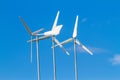 White wind turbines producing alternative energy on blue sky Royalty Free Stock Photo