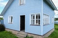 White windows of a small tiny frame house with blue walls,a country residence in sunny summer day