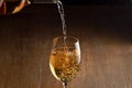 White wine Being Poured into Glass. Stream of wine from bottle and swirls and bubbles in glass. Glass with golden liquid. Royalty Free Stock Photo