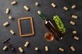 White wine bottle, bunch of grapes, wineglass with corks, corkscrew and chalk board on black background