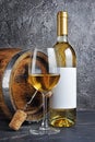 White wine bottle with glass for tasting and wooden barrel with corkscrew in dark cellar Royalty Free Stock Photo