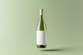 Flying glass bottle with natural white wine with empty white label against tender green background